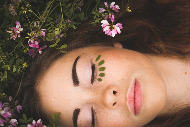 woman with beautiful skin resting in hemp plants and flowers